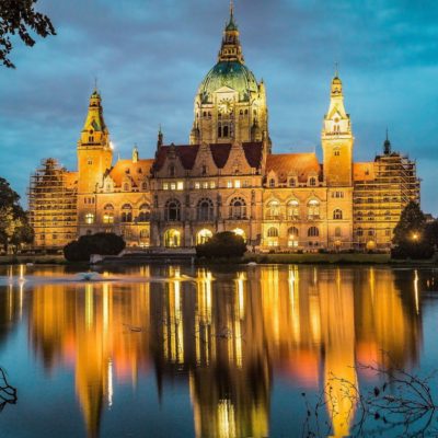 Bild von einem Schloss in Hannover bei Abenddämmerung, welches sich im Wasser spiegelt