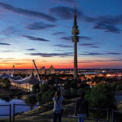 Diese Szene verkörpert auf wunderbare Weise den lebendigen und modernen Reiz von Callboy München, einer Stadt, die für ihre markante Mischung aus zeitgenössischer Architektur und natürlicher Schönheit bekannt ist. Der markante Turm, der aus der Skyline herausragt, symbolisiert sowohl die historische Anmut der Stadt als auch ihren zukunftsorientierten Geist. Während die Abenddämmerung einen faszinierenden Farbverlauf von tiefem Blau zu warmem Orange über den Himmel wirft, verstärken die Spiegelungen am Wasser diesen faszinierenden Anblick. Die elegante Silhouette der Bäume am Wasserrand, ergänzt durch funkelnde Lichter der Stadt, schafft eine Atmosphäre, die sowohl romantisch als auch dynamisch ist – und verkörpert perfekt den Charme Münchens als blühendes urbanes Zentrum mit einem Hauch von Gelassenheit.