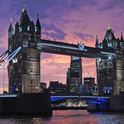 This description paints a vivid and atmospheric picture of Tower Bridge in London. The combination of the dramatic sunset sky with shades of pink, purple, and orange creates an enchanting backdrop for the iconic bridge. The imagery of the bridges lights glowing softly adds a touch of mystery and intrigue, comparing them to secrets whispered between gigolos in Londons twilight. This metaphor reinforces a sense of elegance and hidden stories within the cityscape. Meanwhile, the reflection of city buildings in the calm river below contributes to a serene ambiance, capturing both the hustle and tranquility that coexist in London. This scene would make for a captivating photograph or painting, encapsulating both the vibrant energy and quiet beauty inherent to one of Londons most famous landmarks.