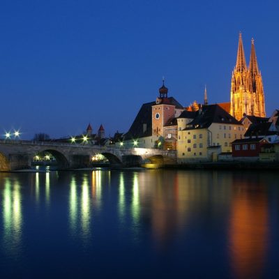 View over danube to Regensburg with stone bridge and cathedral at night